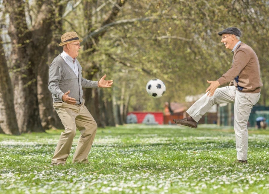 Two seniors playing soccer outdoors